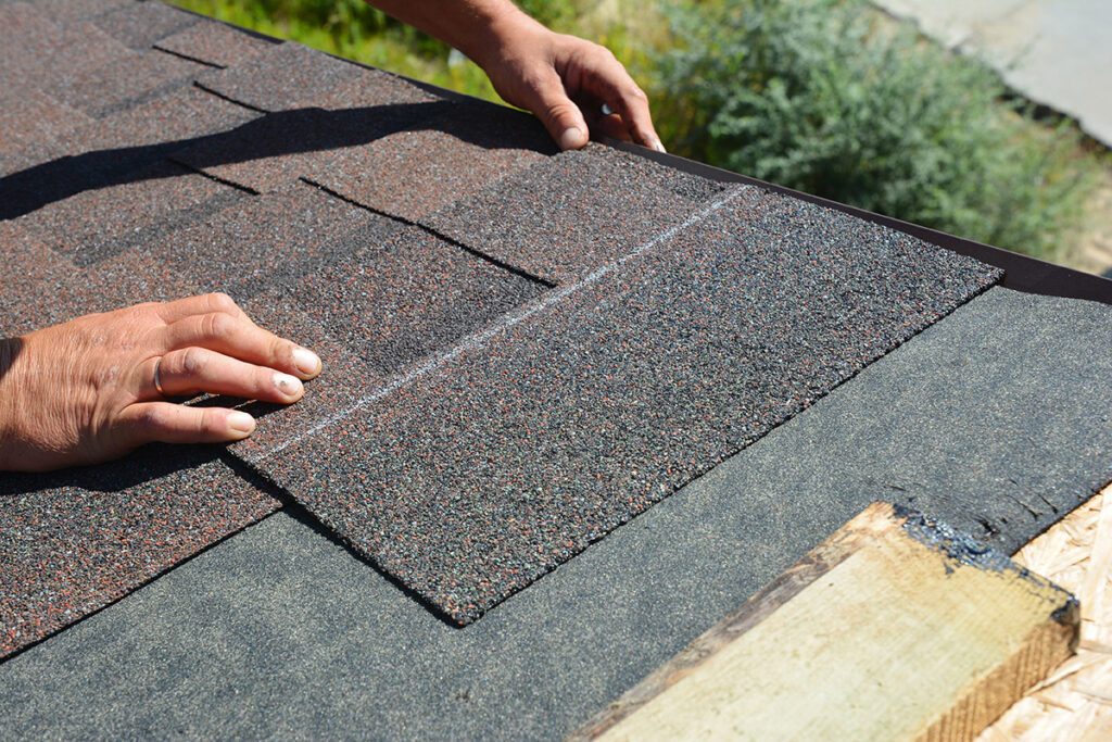 Installaing asphalt shingles on a roof.